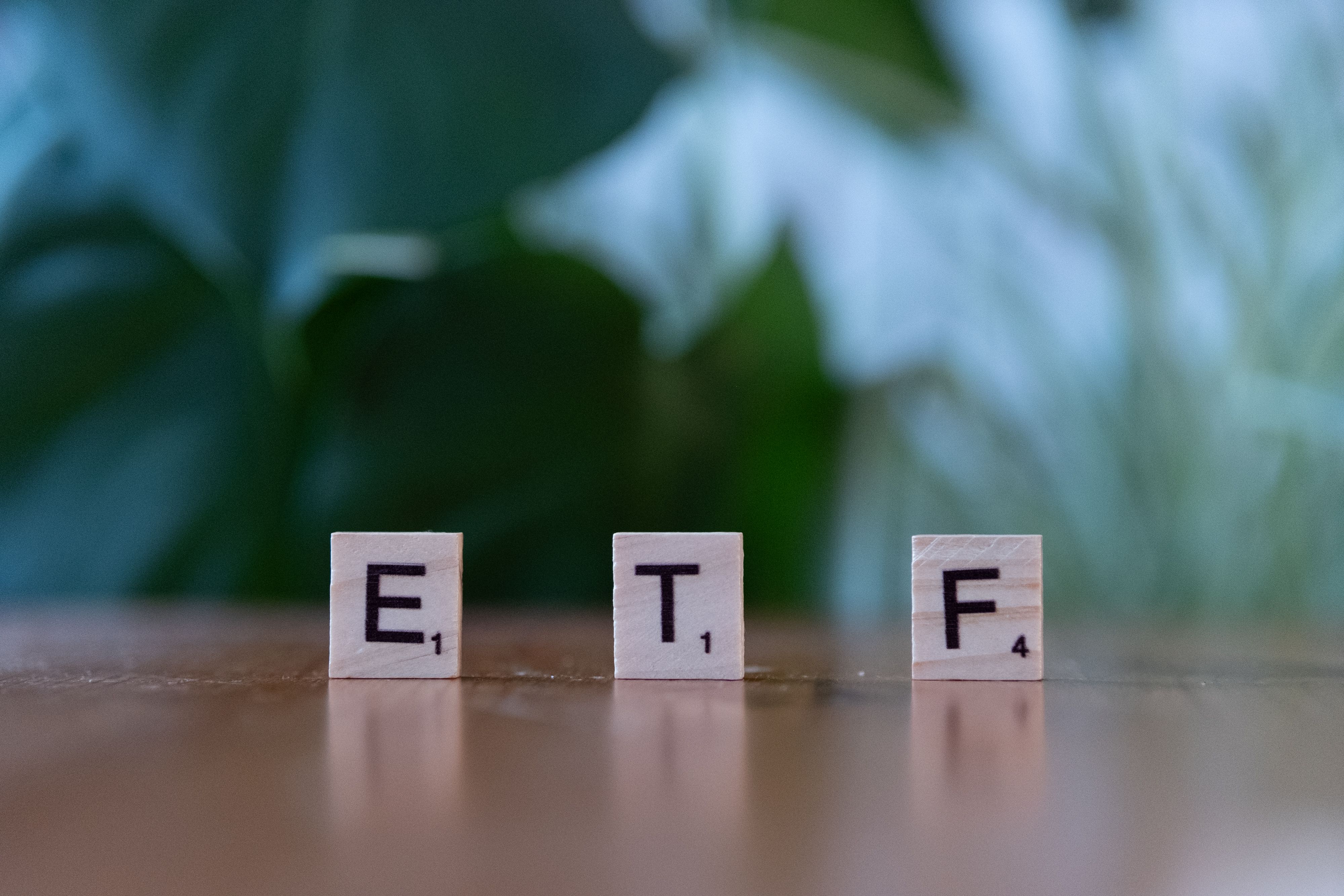 Lettres de jeu de société formant le mot ETF posées sur une table en bois